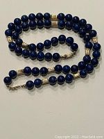 Full view of the lapis bead necklace with gold cylinder spacers and 14k gold clasp