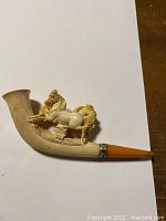 Full profile view of meerschaum pipe showing carved horse design, silver band and amber stem