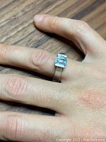 Ring on finger displaying top view of aquamarine gemstone