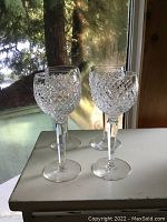 Front angle view of four crystal glasses on white surface by window