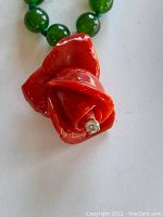 Close-up of red carved coral rose pendant with small diamond at center