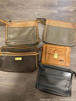 Overview photo of all five vintage Italian accessory bags on wood floor showing various colors, styles, and materials.