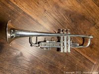 Full-length top-down view of silver-plated trumpet on wood surface