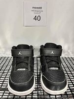 Front view of the black children's Jordans shoes showing the mesh upper and velcro strap with Jumpman logo.