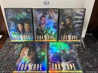 Five Farscape DVD cases arranged on floor showing holographic starburst covers with main characters from the series.