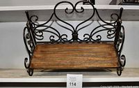 Front view of the foldable shelf showing metal scroll design and wood surface