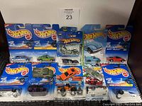 Wide view of various Hot Wheels diecast cars packaged and loose with brand logo and cards visible.