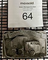 Photo of the vintage limited edition belt buckle showing front metal relief with truck and gas pump design and auction lot number.