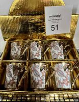 Photo showing set of six gold-tone espresso mugs with floral pattern neatly arranged in gold textured box.