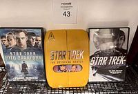 Star Trek The Original Series Complete Season 1 yellow DVD case with Starfleet insignia, flanked by Star Trek Into Darkness and Star Trek (2009) movie DVD cases.