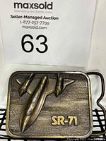 Front view of vintage metallic belt buckle featuring SR-71 Blackbird aircraft and SR-71 lettering.