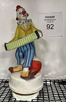 Front view of the vintage clown figurine showing detailed outfit, accordion, and white textured base.