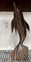 Front angled view of the dark stained wooden dolphin figurine on attached wooden base, showing detailed carving and shape.