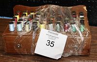 Front and top of wooden sewing box showing colorful spools of thread packed on top, wrapped in protective plastic.