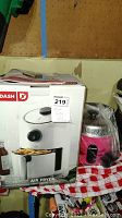 Dash compact air fryer and Tatung mini slow cooker together in packaging, second lot photo shows the front of the Dash air fryer packaging, third photo shows Dash air fryer instruction manual with model number.