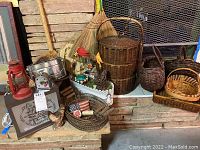 Red vintage railroad lantern, cast iron rooster doorstop, pie bird, metal box lamp, various woven baskets and decorative items arranged on stone hearth.