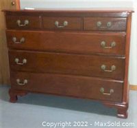 Front view of heavy vintage wooden dresser showing five drawers with brass handles, in used condition with scratches and scuffs.