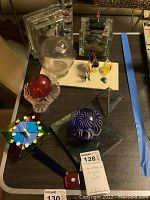 Full tray of various glass items including Galileo thermometer, glass clocks, and paperweights.