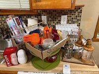 Full view of green two-level Lazy Susan filled with kitchen measuring tools, glass soap dispensers, measuring cups, and paper goods such as foil and parchment paper rolls.