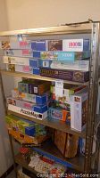 Shelving displaying many boxed jigsaw puzzles of varying sizes and brands including Ravensburger.