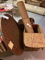 Photo of large flat wicker tray, oval shaped, brown finish, standing upright behind other items