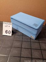 Closed blue zippered storage case with a textile exterior and visible logo on the front lower corner.