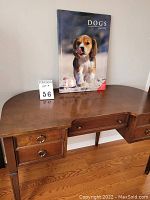 Photo of the book standing on a wooden desk, showing the front cover and lot number card.