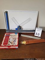 Photo showing drafting board with adjustable rulers, Staedtler architect scale ruler, leather case, and Shaffer Calligrapher ink set box.