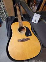 Front view of Epiphone PR-200 guitar body in open case showing spruce top and black pickguard