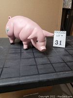 Front and side view of the large pink piggy bank showing detailed face, legs, and small floral pattern on the side.