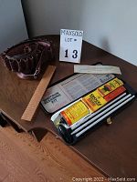 Leather cartridge belt and Winchester shotgun cleaning kit laid out on wooden table showing all items in lot.