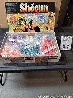 Open box top with sealed bags of multi-colored plastic game pieces and box lid artwork
