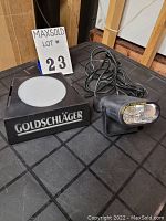 Two stroboscopic image lights labeled Goldschläger with diffuser tops, placed on black table surface.