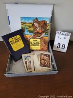 Photo showing the two books and the full deck of tarot cards displayed on a table inside the lid of a white box.