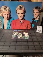 Color hardboard poster featuring The Police band members in front view, three men, arranged horizontally.