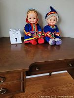Photo showing both vintage Ideal Toy Corporation dolls seated on a wooden surface with lot number sign