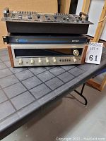 Three stacked vintage electronic devices on a folding table including a Pioneer SX-828 stereo receiver at the bottom, Elite EP160 amplifier in the middle, and Pyramid audio mixer on top.