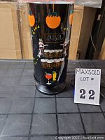 Front view of vintage cylindrical bar-themed light with dancing figures and tropical drink illustrations on black background