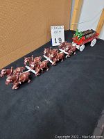 Full side view of the entire set showing 8 horses pulling beer wagon with driver, passenger and barrels.