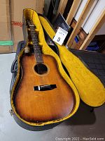 Opened guitar in yellow plush-lined hard case showing sunburst top and guitar body