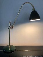 Full side view of the British Best crane lamp showing the green base and adjustable arm with black power cord