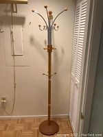 Full view of coat rack showing wood post and chrome hooks