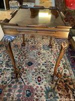 Front view of the wooden coffee table showing carved claw feet and the drawer.