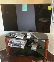 Full view of the entertainment console with Panasonic 55-inch TV on top, Samsung 3D Blu-ray player, cables, and other items on shelves.