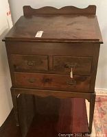 Front view of wooden slant top desk showing three drawers and scalloped backsplash.
