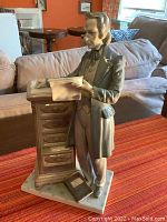 Full view of the Lladro attorney figurine standing beside a small cabinet holding papers, showing front and base.