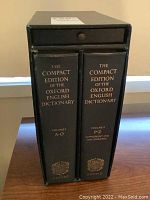 Two black hardcover volumes of The Compact Edition of the Oxford English Dictionary in black slipcase box, spines showing volume I A-O and volume II P-Z Supplement and Bibliography.