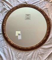 Full overhead view of round mirror on white fabric background reflecting ceiling vent.