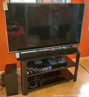 Full frontal view of TV mounted on stand with soundbar and components below
