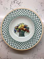 Close-up of bowl showing fruit basket motif and green lattice border with gold trim